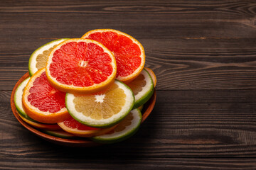sliced green and orange grapefruits in a plate on a wooden background