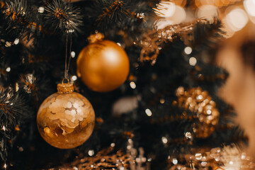 Golden Christmas balls hanging on the Christmas tree. Bokeh magic effect. Festive winter holiday background