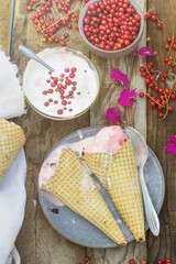 Homemade ice cream with red currants in a waffle cone on a summer day. Fresh berries