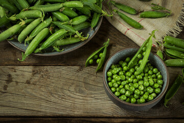 Green peas peeled and in pods on a wooden background