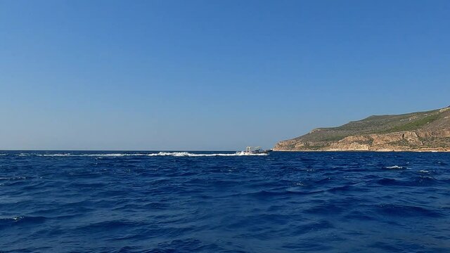 Approaching Levanzo Sicilian island with cruising touristic dinghy boat, Sicily in Italy. Slow-motion low-angle sea level pov