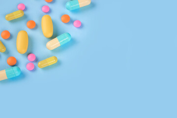 Assorted medicine pills, capsules and tablets on blue background with copyspace. Immune system vitamins and supplemets