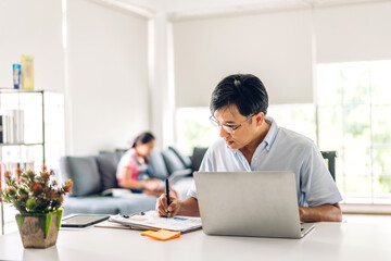 Obraz premium Asian man relaxing using laptop computer working and video conference meeting chat with girl daughter use laptop computer learning with online education e-learning system at home.work from home