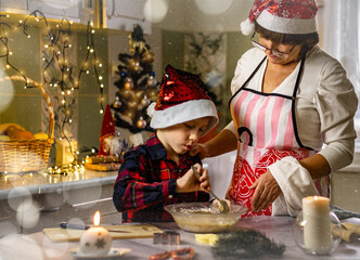 Christmas family traditions, a grandmother in a New Year's cap is cooking gingerbread with her grandson in the home kitchen