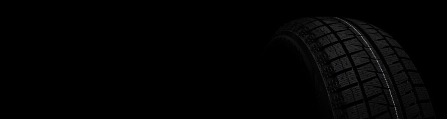 black tire with winter tread on a black stylish background close-up