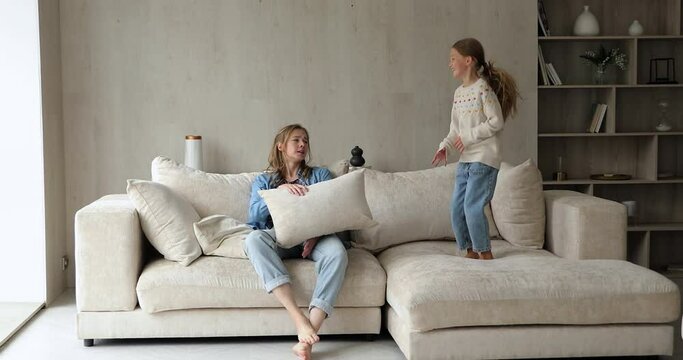 Give me a break. Tired overworked mom sit on couch refuse play with naughty active small daughter. Hyperactive little girl trouble demand attention require amusements from exhausted teen older sister