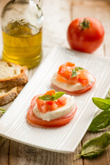 Caprese salad traditional italian recipe with mozzarella tomato basil and bread over white dish