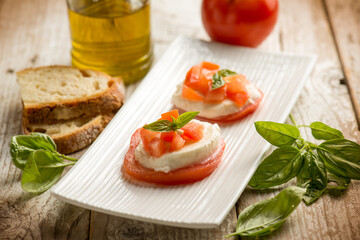 Fototapeta na wymiar Caprese salad traditional italian recipe with mozzarella tomato basil and bread over white dish