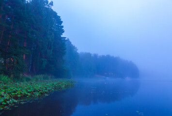 Wooden bridge made of boards on calm lake, evening sky and fog