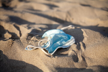 Fototapeta na wymiar Pollution by disposable medical mask on beach by sea due coronavirus pandemic.