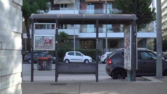 Shot of a bus stop and vehicles passing by, people commuting
