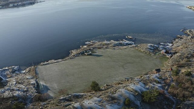 Drone top view shot of a football soccer field on a rocky island on a sunny winter day at Öckerö Island Municipality in Gothenburg archipelago, Sweden.