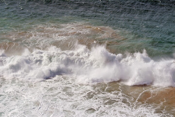 A big wave in the Atlantic Ocean with a strong wind. 
A strong wind carries the spray far away, creating a continuous whitish veil.
