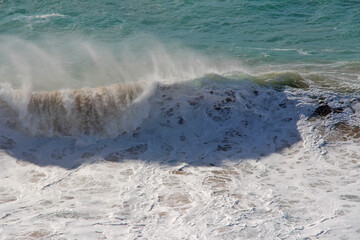 A big wave in the Atlantic Ocean with a strong wind. 
A strong wind carries the spray far away, creating a continuous whitish veil.
