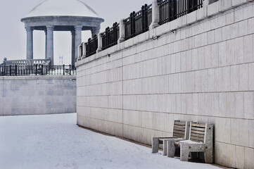 Snowfall on the city's granite embankment with a marble rotunda and balustrade. Snowflakes are...