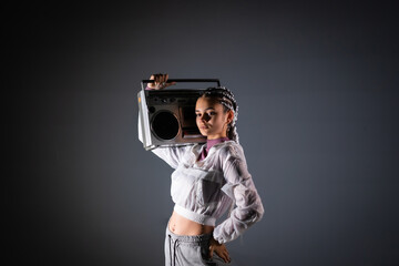 Portrait of a young girl with white braids with a vintage boombox, black background, 80s style, retro photography