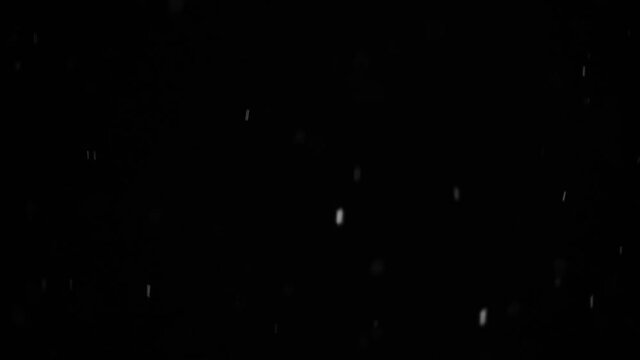 Bokeh of white snow on a black background. Snowfall - design element hd slow motion video.