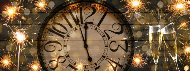 HAPPY NEW YEAR 2022 - Festive silvester New Year's Eve Party background panorama banner - Golde fireworks, sparklers, clock and champagne classes toasting on black wooden wall texture in the night
