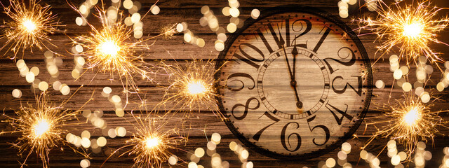 HAPPY NEW YEAR 2022 - Festive silvester New Year's Eve Party celebration background panorama banner long - Golden yellow fireworks, sparklers and clock on rustic brown wooden wall texture in the night