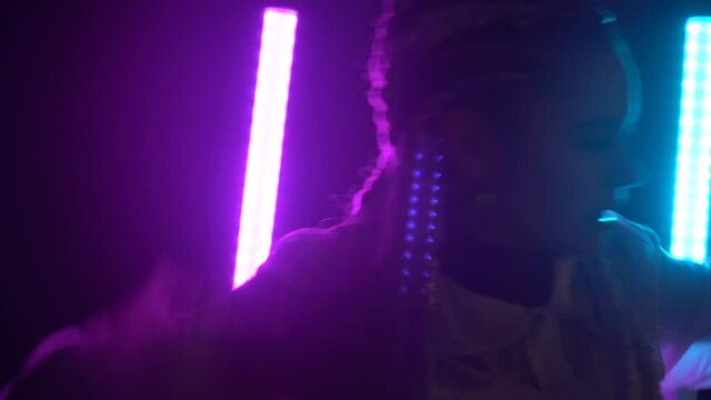 Dancing detail of rap dancer dancing with neon lights against, head and shoulder movements with blue and pink light, 4k video