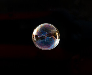 One soap bubble floating in the air with a black background