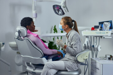Young woman working in a dentist’s office and talking with patient