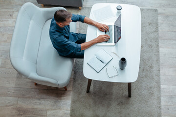 young man is working on a laptop in his apartment.