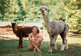 Woman sitting with alpacas at farm