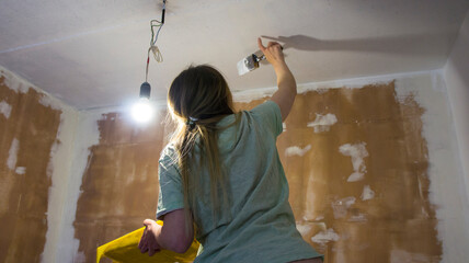 Renovation of the room, the girl performs painting work