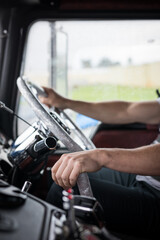 Naklejka premium Caucasian male truck driver arms hands steering wheel cabin drive commute work steer