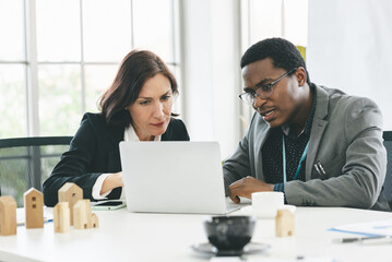 Serious working smart business man with African American and middle age business woman with white skin in office 


