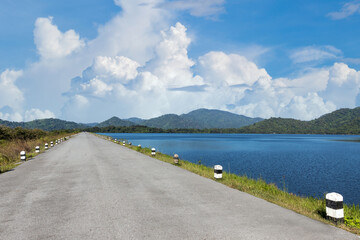 Driving on an empty road. Empty asphalt road through the green field and clouds on blue sky in summer day. Open road ahead, endless road for concept.