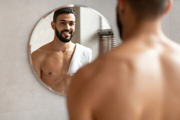Confident young Arab guy looking in the mirror