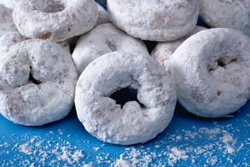 Fototapeta na wymiar Powdered mini donuts or doughnuts on blue