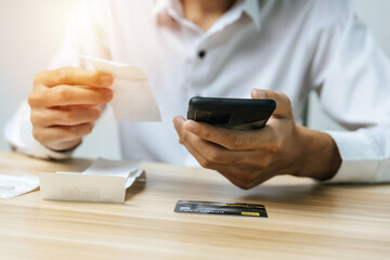 people hand using digital mobile phone scan and payment online with credit card bill on desk in home office, electronic payment, money cost saving, online shopping, business finance, expenses concept