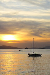 Alone sailboat at sunset. Atmospheric seascape with orange sun