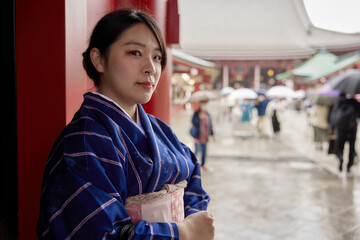 浅草寺の前で微笑む紺の着物を着た日本人女性