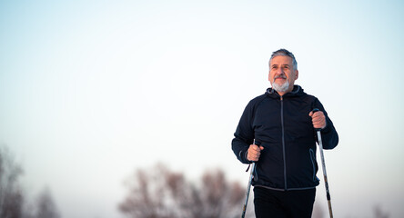 Senior man nordic walking outdoors on a snowy, winter day