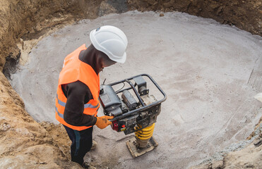 Worker uses a portable vibration rammer at construction of a power transmission substation