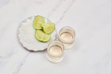 Mexican Gold tequila with lime and salt on marble table.
