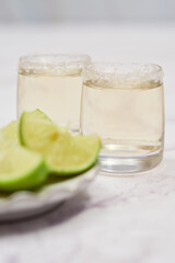 Shot of tequila with lime and salt on white background