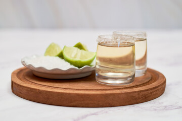 Mexican Gold tequila with lime and salt on marble table.