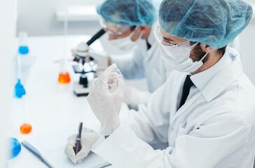 close up. a scientist looking at a bottle of a new vaccine.