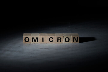 wooden blocks with the word omicron as symbol for covid-19 crisis
