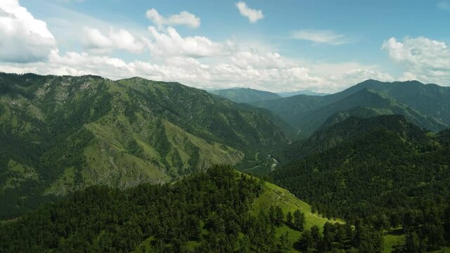 A camera hit a mountain range covered with green trees.