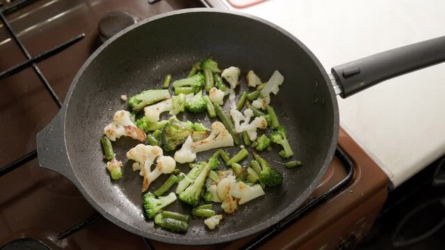 female hands adds a scrambled eggs to fried vegetables while cooking omelette