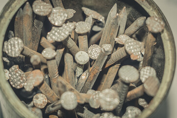 Blurred rust iron nails close-up in an iron jar. Iron pin covered with dust and rust. Selective focus, dust on surface.
