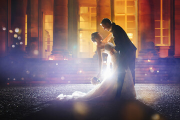 Gorgeous bride and stylish groom dancing at night - First wedding dance with a beautiful golden light