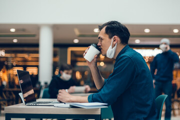 young man with a coffee takeaway sitting at a cafe table