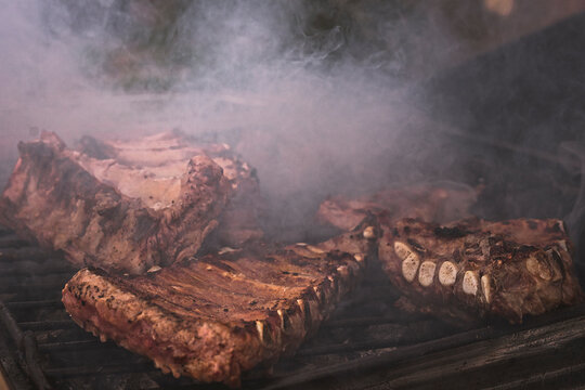 Costillas de cerdo ib&eacute;rico haci&eacute;ndose a la brasa en la parrilla al aire libre en el campo.